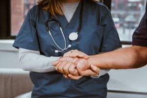 A nurse holding a patients hand