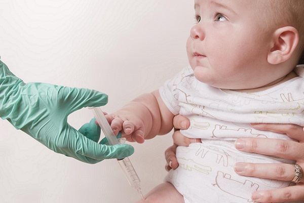 photo of gloved hand giving baby a vaccine
