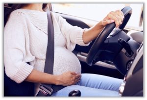 A pregnant person driving a car 
